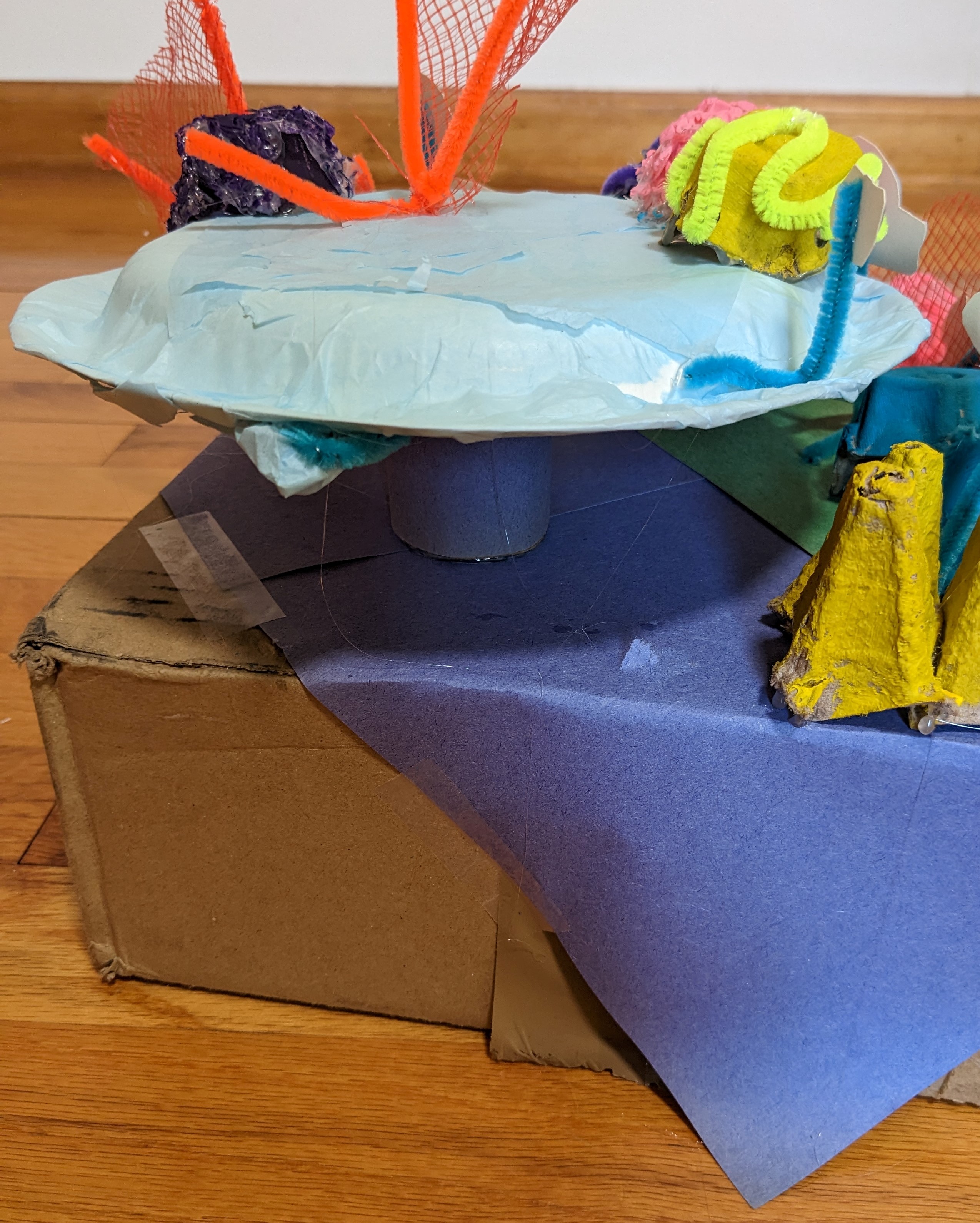 A paper plate and a cardboard box stacked to make the base of the reef.