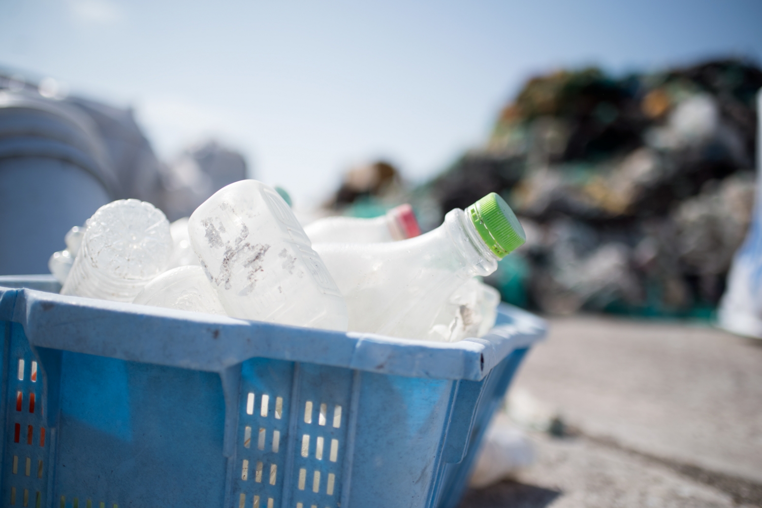 A blue box of plastic bottles on a beach.