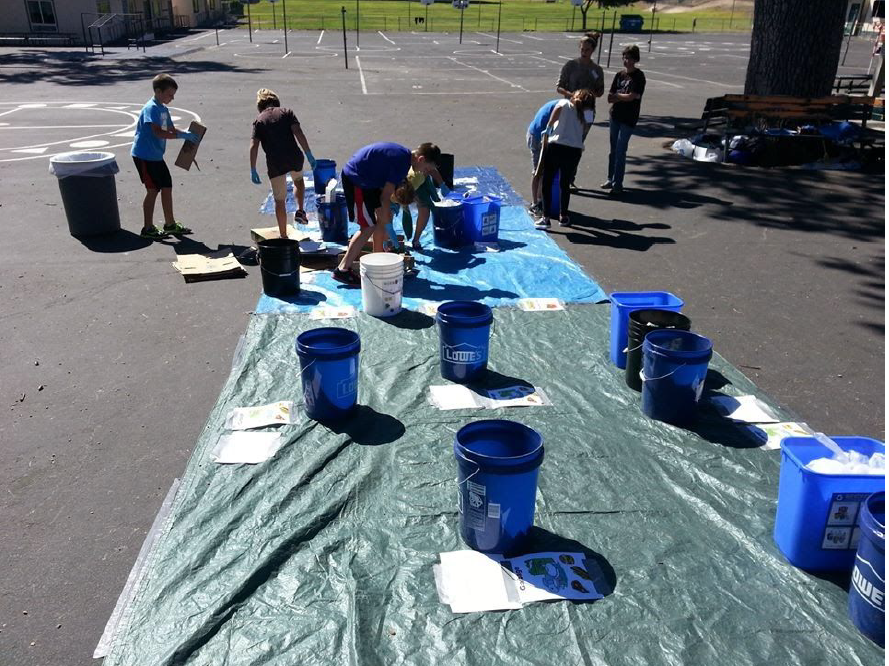 A group of people sorting trash into blue buckets.