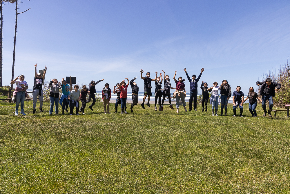 A group of students jumping in celebration on a green field.