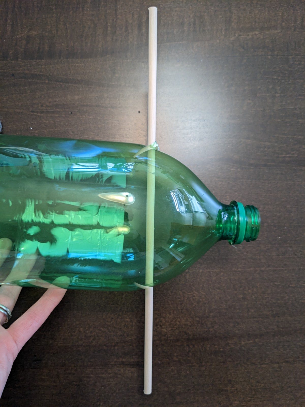 A dowel stuck through the bottle. 