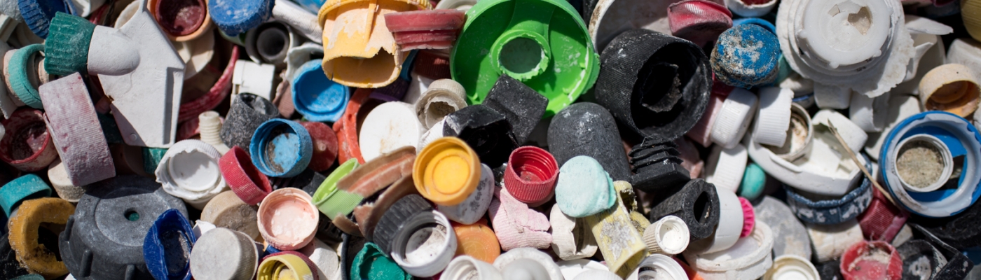 Assorted old plastic bottle caps in a variety of colors, shapes, and types.