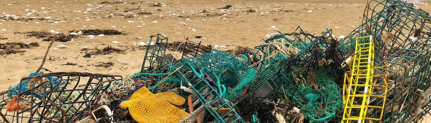 A pile of derelict fishing line, nets, traps, and other debris on a beach.