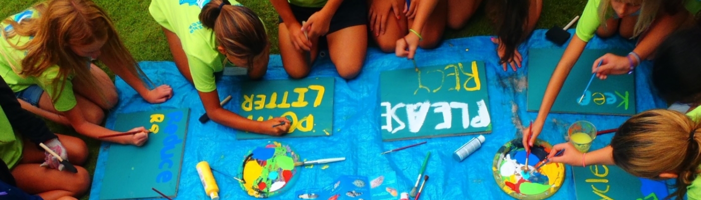 Kids painting signs on a tarp.