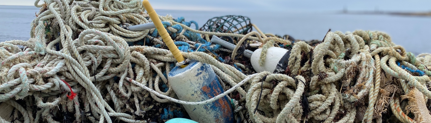 Rope, line, buoys, and other fishing gear on a rocky beach.