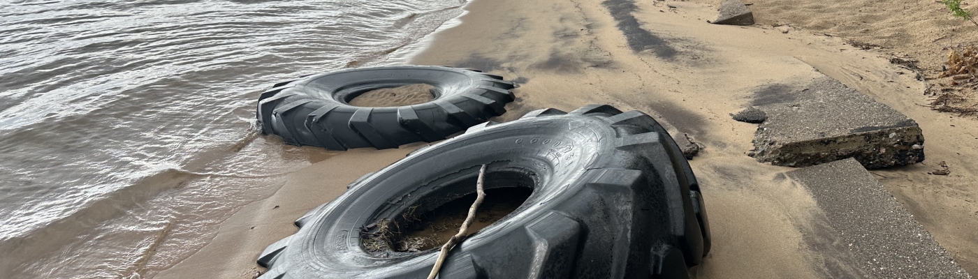 Two large tires stuck in Lake Superior beach sand.
