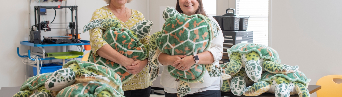 Two women holding stuffed turtles