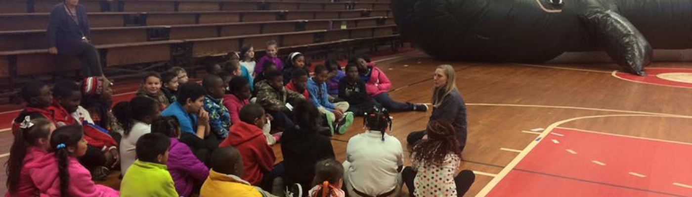 Students sit on the floor in discussion with the inflatable whale classroom in the background.