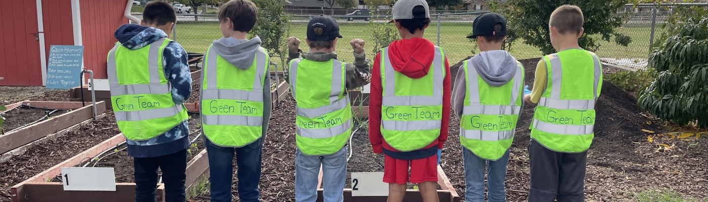 Six students wearing "Green Team" jackets lined up in a schoolyard.