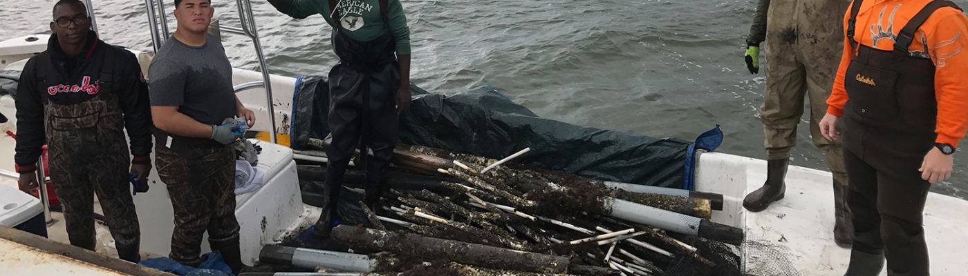 Five volunteers stand in a boat loaded with debris.