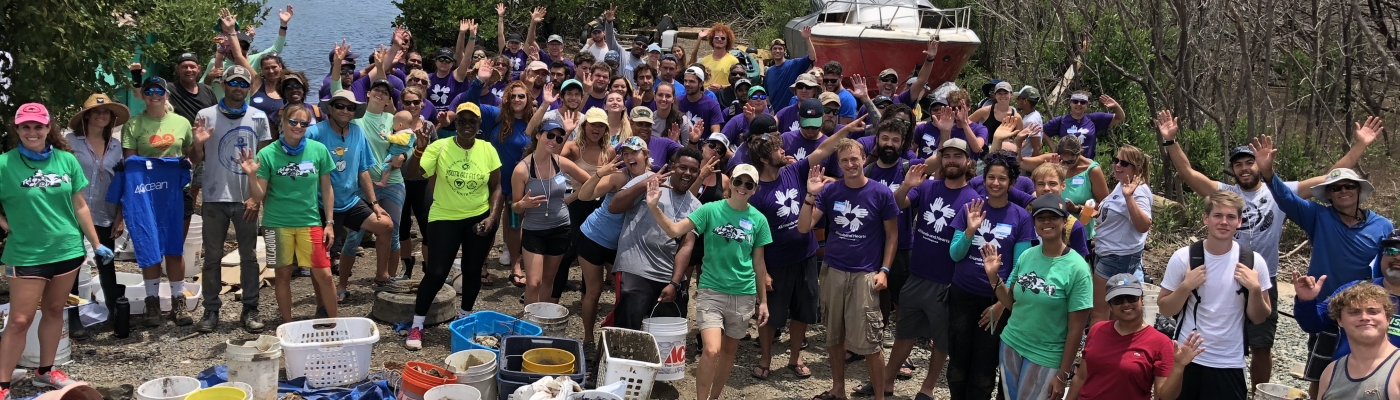 Volunteers stand together in a large group and smile for a picture.