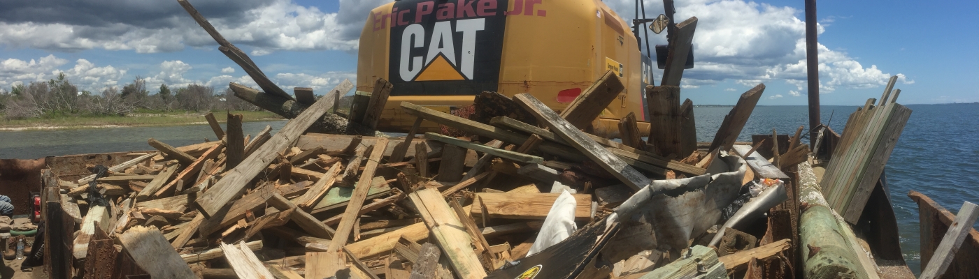 A large, messy pile of lumber being collected with heavy machinery. 