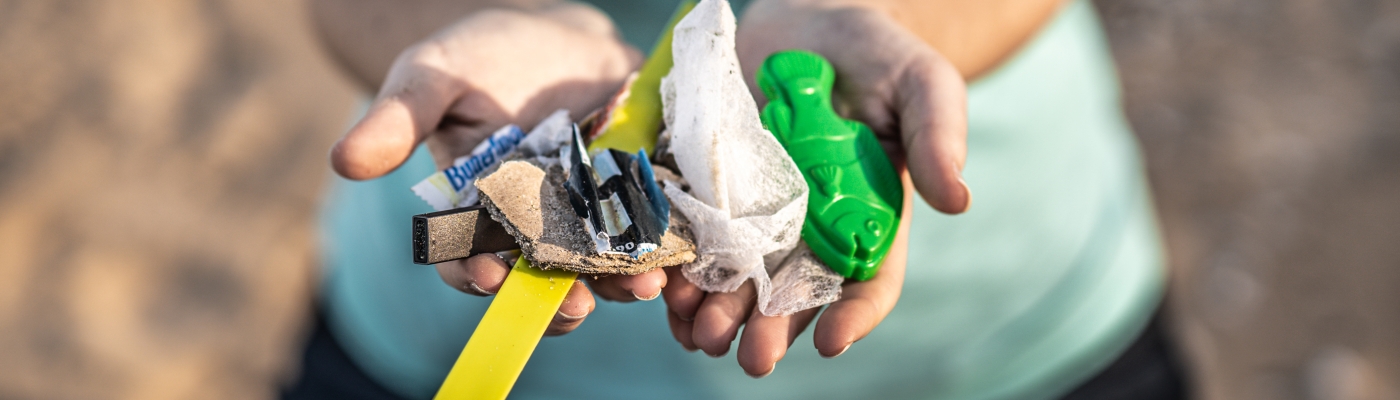 Hands holding out marine debris collected from a lake shoreline.