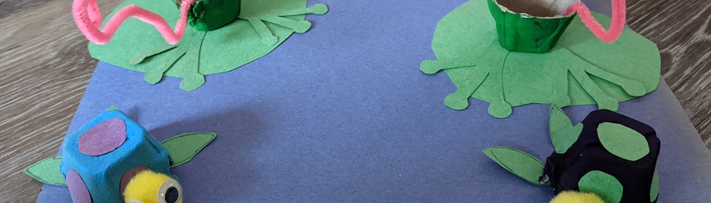 A pond made of blue construction paper with recycled-egg-carton frogs and turtles.