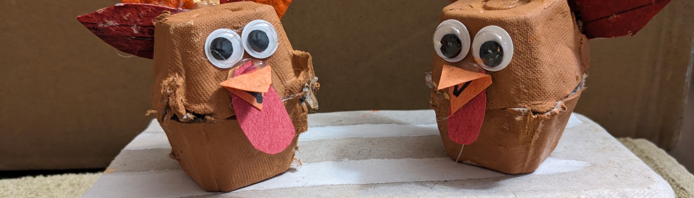 Two turkeys made of egg cartons sit against a plain background.