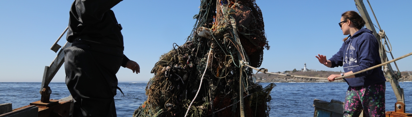 A large mass of derelict fishing gear getting hauled onto a vessel.
