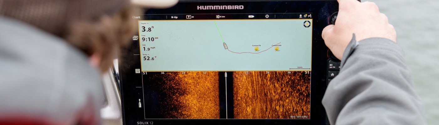 A person on a boat looking at a tablet screen that shows the location of crab pots.