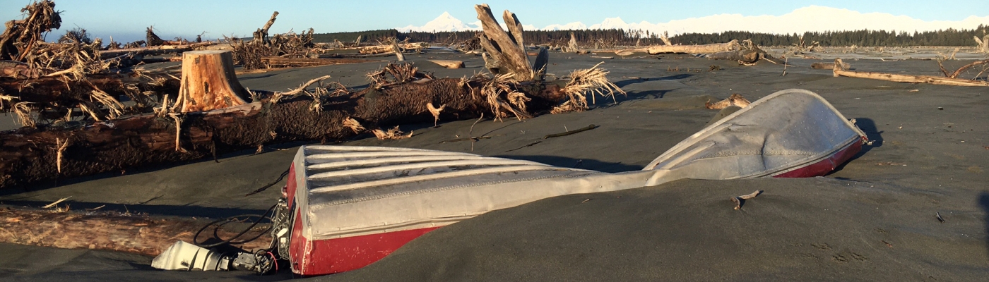 A damaged skiff partially buried in the sand.
