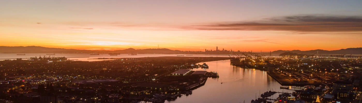 An aerial view of a waterway through an urban area at sunset.