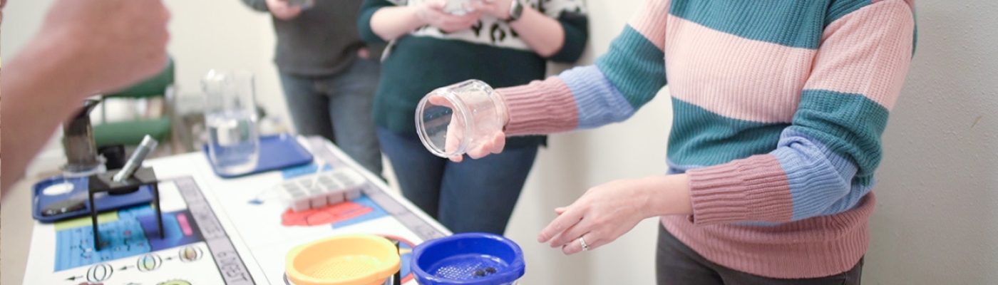 Workshop participants at a table pouring containers of water through a filter that traps debris in the water.