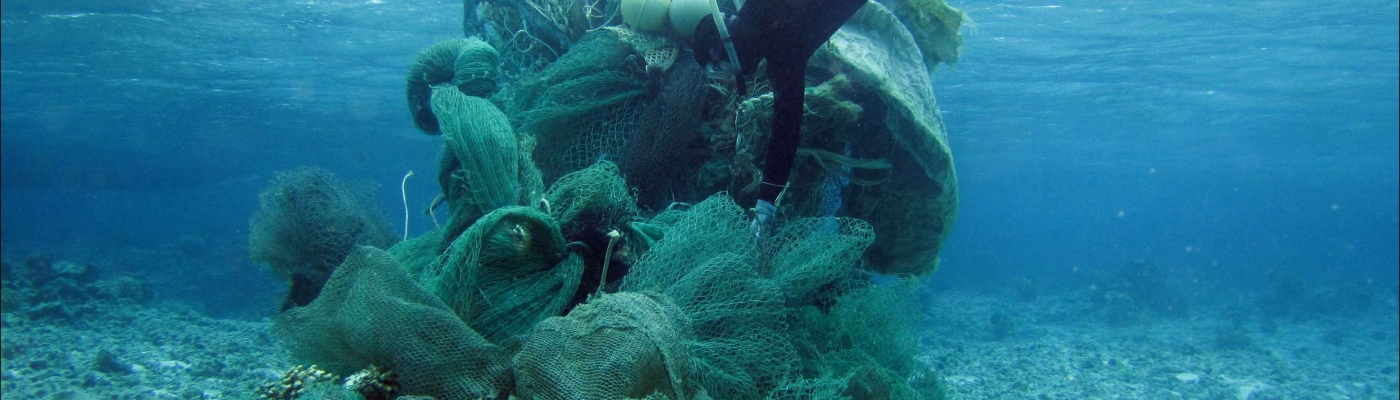 Scuba diver managing a huge wad of derelict fishing net bundled for removal.