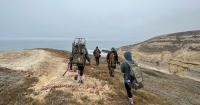 A group of people hike towards the ocean.