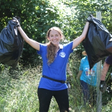 A volunteer smiling and holding up two bags of collected debris.