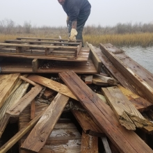 A person bends down to pick up some lumber in a pile that was created by a hurricane in North Carolina.