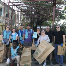 A group of people smile for a picture while holding large, paper bags that will be used to collect trash.