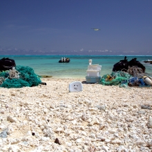 Two piles of marine debris collected from separate 300-m shoreline segments are staged to be loaded onto the small boat. (NOAA PIFSC Coral Reef Ecosystem Program) 