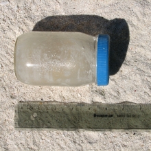 Glass mayonaise jar found on the beach. Though the jar has a plastic lid, the external material type is predominantly glass, thus it is classified as 'glass jar'.