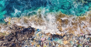 A wave crashing on shore into a pile of marine debris.