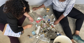 Two volunteers sorting through miscellaneous marine debris items and categorizing types of marine debris on a tracking sheet.