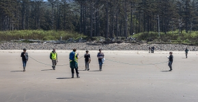 Students lined up on a beach with measuring rope.