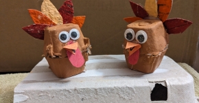 Two turkeys made of egg cartons sit against a plain background.