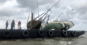 Abandoned boats loaded on a salvage vessel.