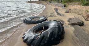 Two large tires stuck in Lake Superior beach sand.