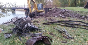 A man surveys large debris items with a crane in the background.