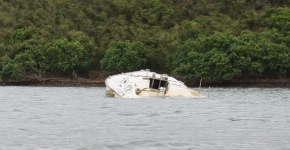 A derelict vessel partially-submerged in water.