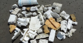 Broken white Styrofoam packing, refrigeration insulation, and other debris o0n a beach.