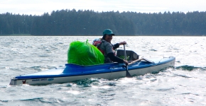 A volunteer in a kayak with a bag of debris.