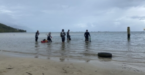 A marine debris removal dive team on the beach, preparing to enter the ocean.