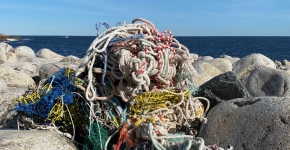 A mound of ropes, net, and other fishing gear piled on a rocky shoreline.