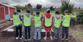 Six students wearing "Green Team" jackets lined up in a schoolyard.