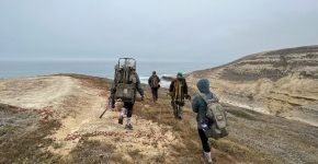 A group of people hike towards the ocean.