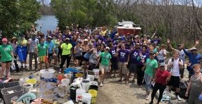 Volunteers stand together in a large group and smile for a picture.