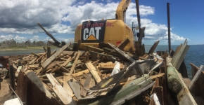 A large, messy pile of lumber being collected with heavy machinery. 