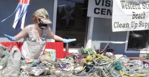 A person with gloves at a table covered in collected marine debris.