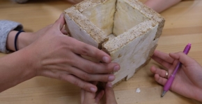 Hands hold up the four sides of a structure made from mycelium fungus.