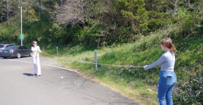 Two people in a parking lot stretching a long string.